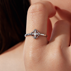 Close worn view of the same four-lobed quatrefoil moissanite ring on the original wearer’s hand.
