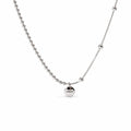 Sterling Silver Eira necklace with round LUCKY medallion, beaded and smooth chain sections, in the existing cropped tabletop view with white studio treatment and soft shadow; AI studio edit and enhancement of the existing supplier source view; chain ends extend beyond the frame.