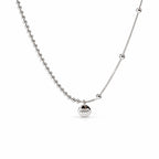 Sterling Silver Eira necklace with round LUCKY medallion, beaded and smooth chain sections, in the existing cropped tabletop view with white studio treatment and soft shadow; AI studio edit and enhancement of the existing supplier source view; chain ends extend beyond the frame.