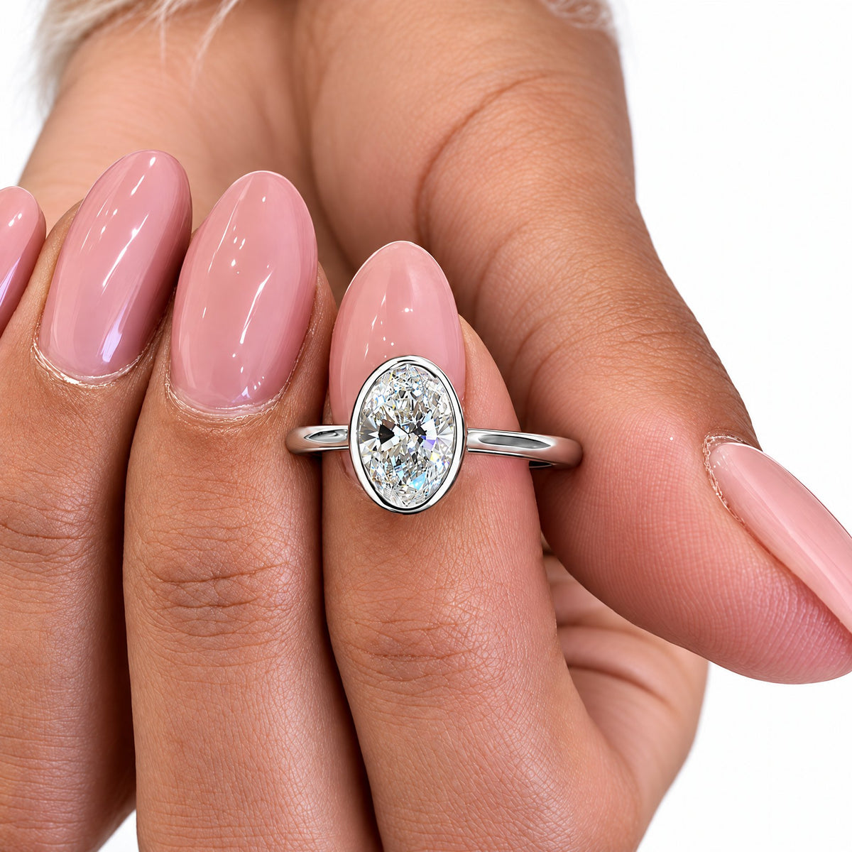 Sterling Silver oval moissanite bezel-set ring worn on a finger, preserved in the original supplier photo pose with white studio surroundings and soft lighting; studio edit and AI enhancement of the existing view.