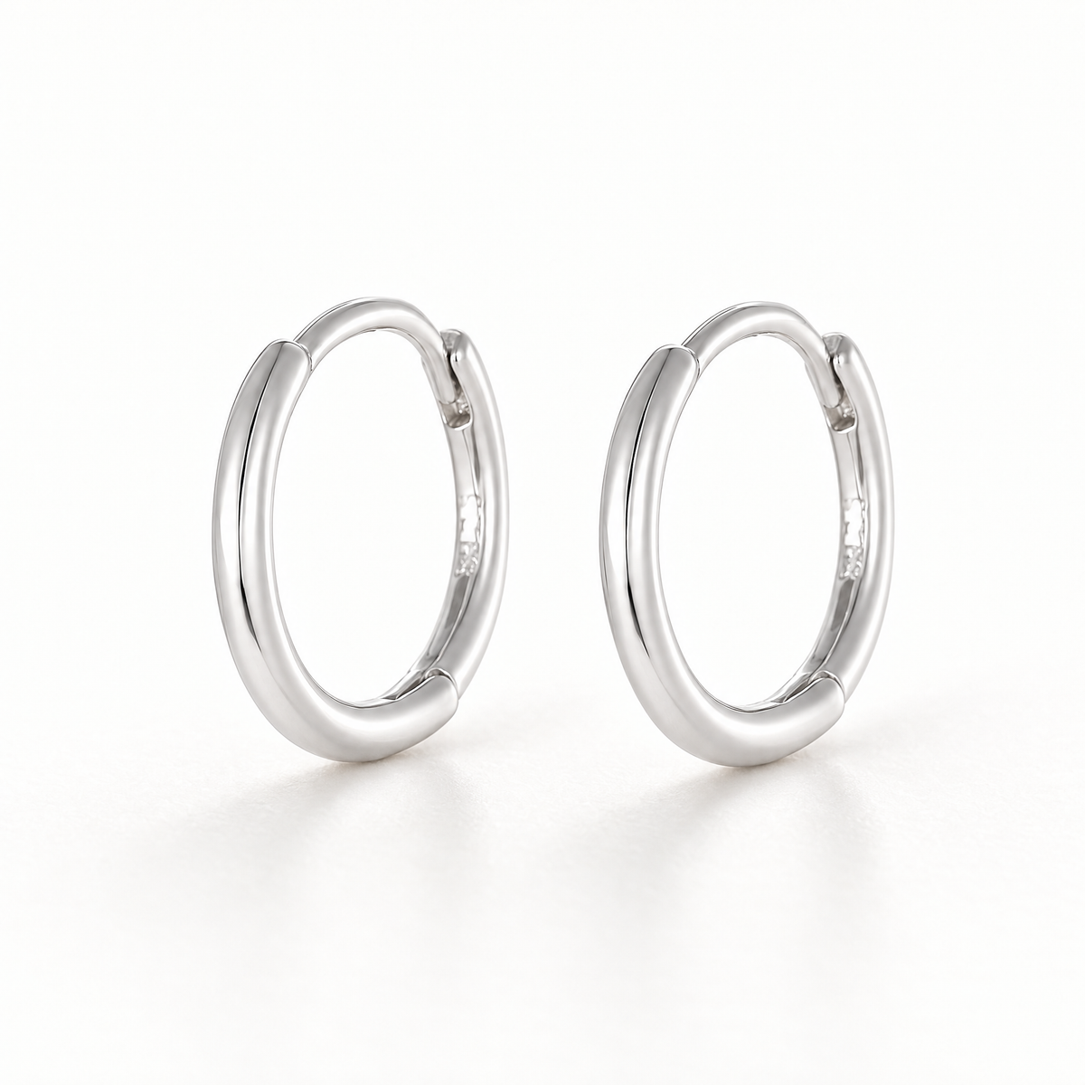 The Kiri Huggie Hoops — Silver pair — upright three-quarter studio view; reference-based AI visualization