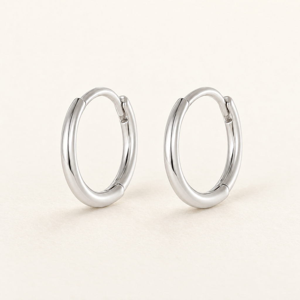 The Kiri Huggie Hoops — Silver pair — closure-focused cream studio view; reference-based AI visualization
