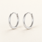 The Kiri Huggie Hoops — Silver pair — closure-focused cream studio view; reference-based AI visualization