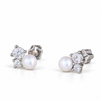 A pair of asymmetric 925 sterling silver stud earrings with pearl decoration and moissanite details, shown from the front on a white studio background.